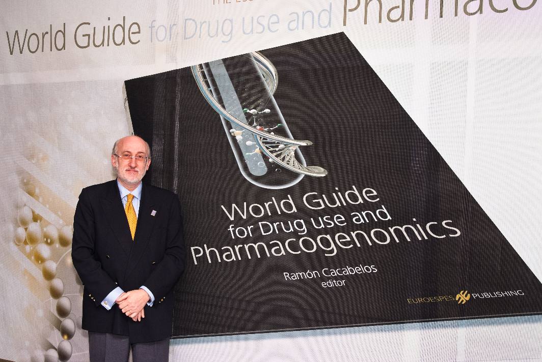 Un hombre con traje se encuentra de pie junto a una gran exposición de un libro titulado "Guía mundial sobre el uso de medicamentos y la farmacogenómica", editado por Ramón Cacabelos. El fondo presenta un diseño de portada de libro similar.