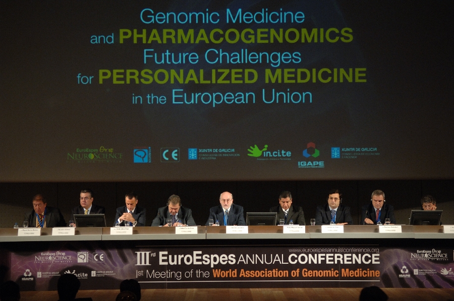 Un panel de ponentes sentados en una mesa durante la III Conferencia Anual de EuroEspes. La pantalla detrás de ellos muestra el tema de la conferencia sobre medicina genómica y farmacogenómica en la UE.