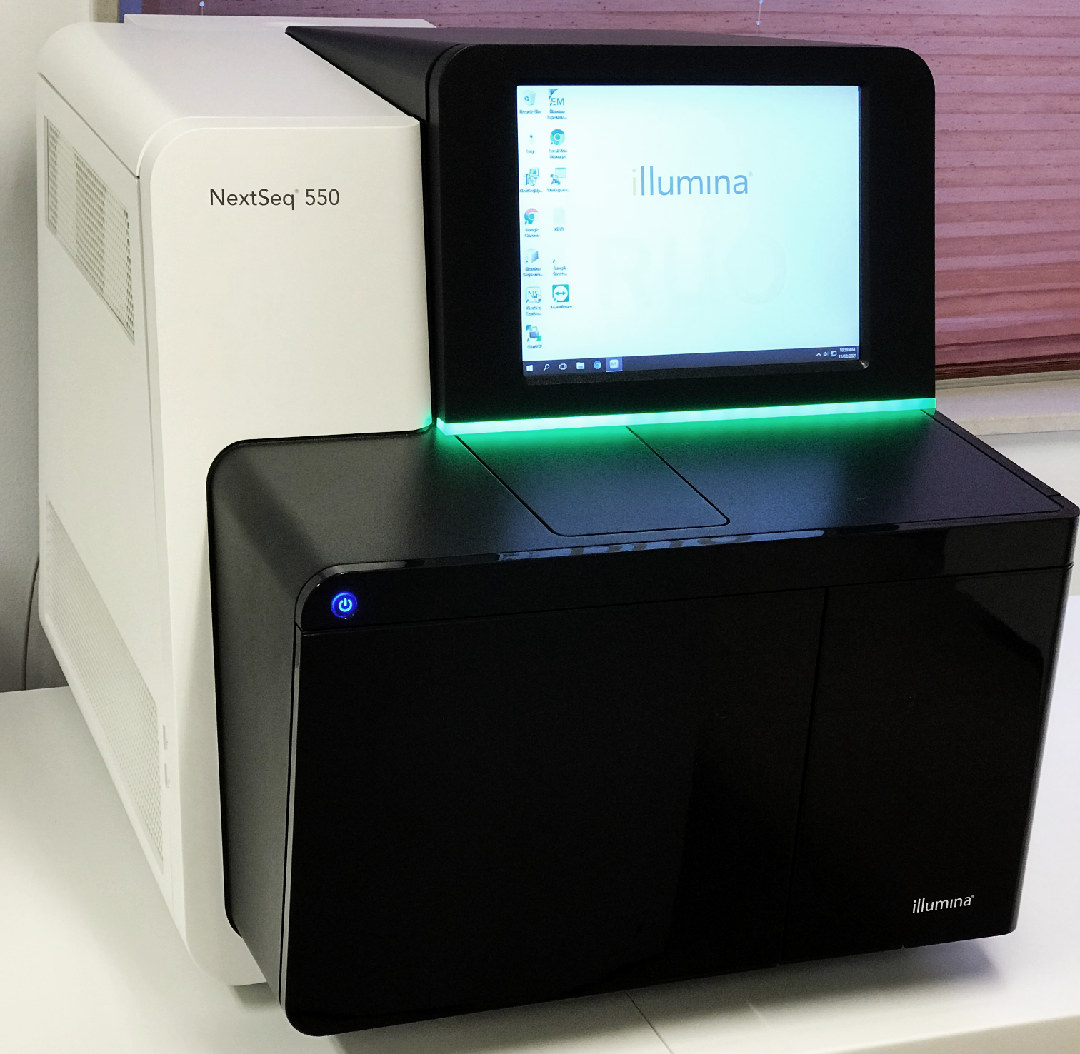 La máquina de secuenciación de ADN NextSeq 550 de Illumina cuenta con un elegante diseño en blanco y negro, adaptado a las aplicaciones de NGS. Su intuitiva interfaz de pantalla táctil muestra con orgullo el logotipo de Illumina, todo ello colocado elegantemente sobre una superficie blanca en un entorno bien iluminado.