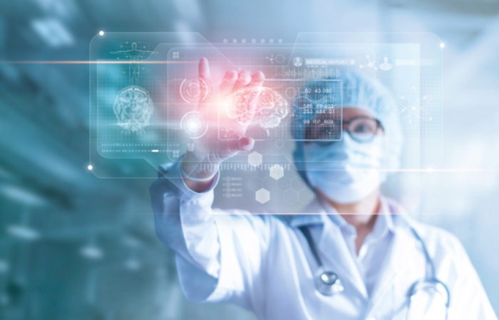 Un profesional sanitario con bata de laboratorio y mascarilla quirúrgica interactúa con una pantalla transparente que muestra datos médicos digitales, incluidos escáneres cerebrales y estructuras moleculares, en un entorno futurista del Boletín Médico EuroEspes Health.