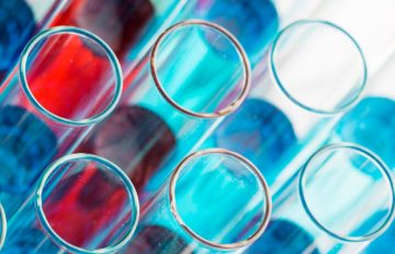 Primer plano de varios tubos de ensayo con líquidos de vibrantes tonos azules y rojos, que recuerdan a una actualización de salud del Boletín Médico EuroEspes. Dispuestos en forma de cuadrícula, presentan un llamativo contraste de colores, indicativo de un intrigante experimento científico o entorno de laboratorio.